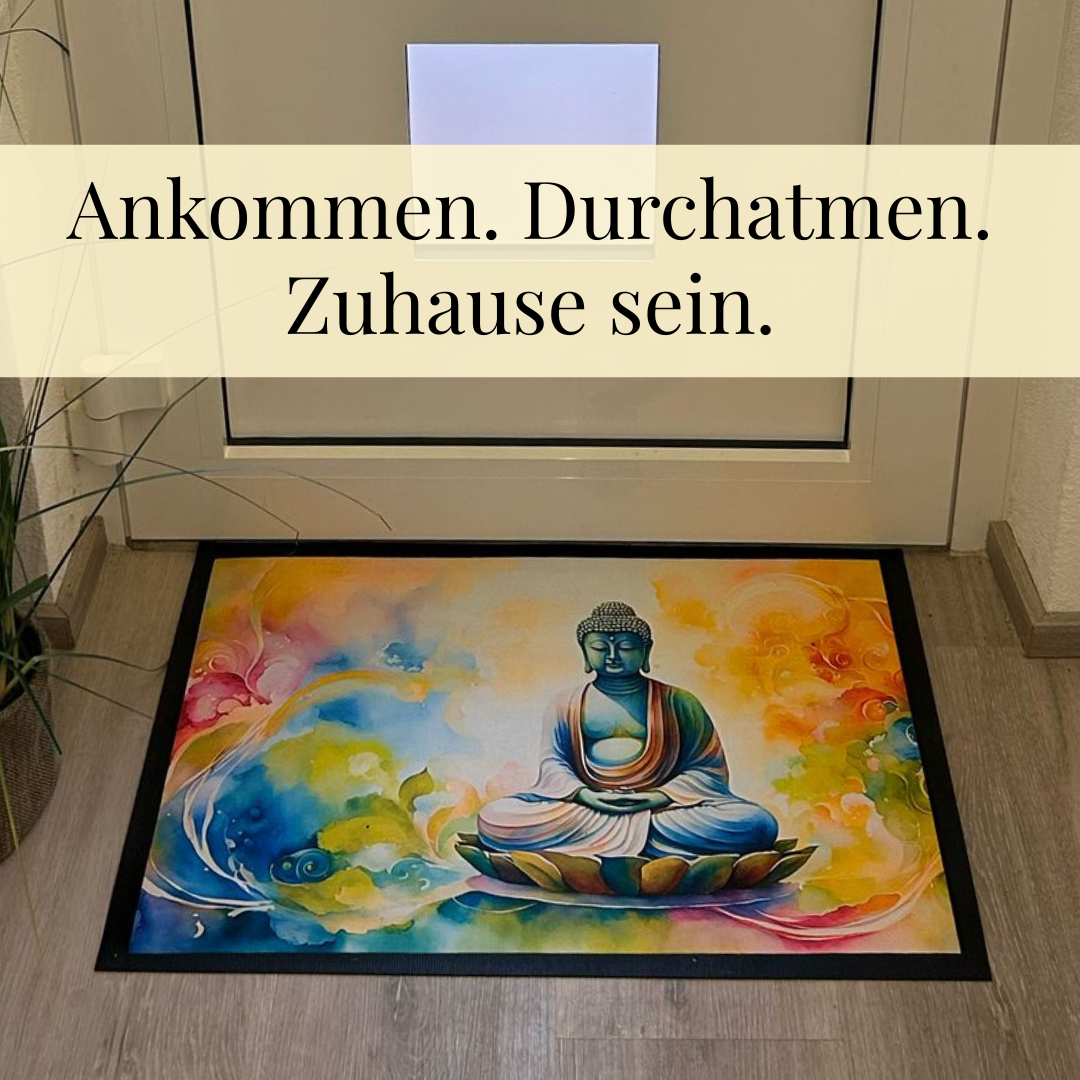 Farbenfrohe Fußmatte mit meditierendem Buddha-Motiv vor Haustür, begleitet vom Slogan ‚Ankommen. Durchatmen. Zuhause sein.‘